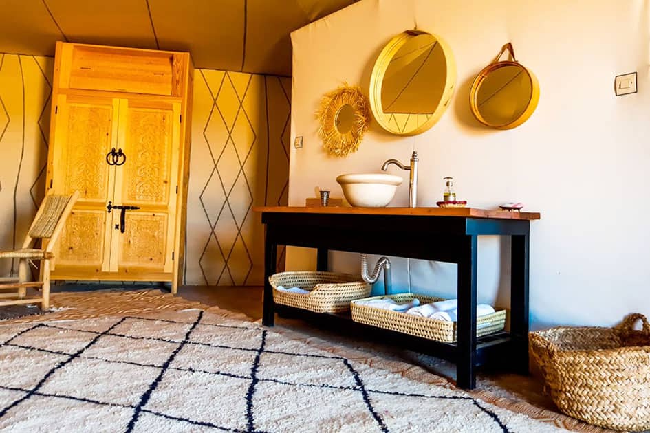 Inside a tent at Madu Premium Camp, with a washbasin and Moroccan rug