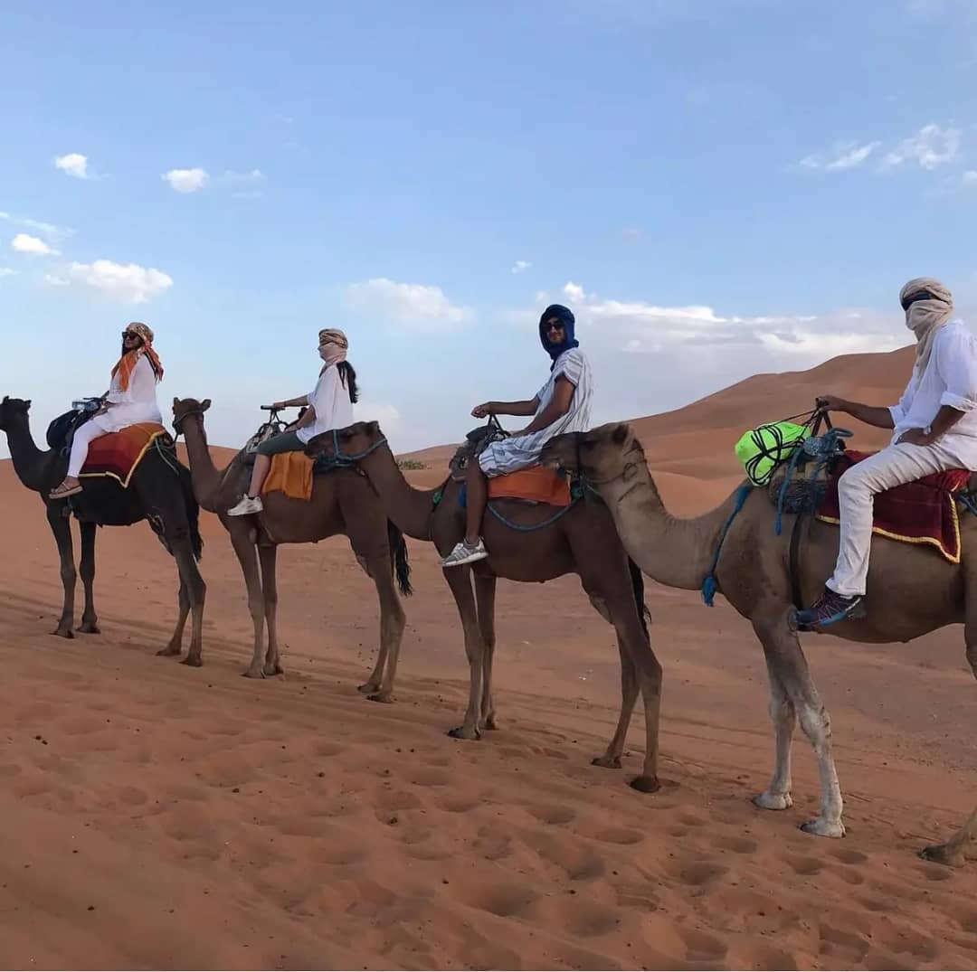 A family riding camels in a line across the Sahara dunes near Merzouga