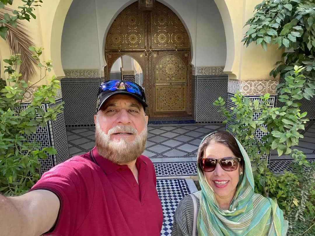 Couple taking a selfie in a zellige-tiled courtyard with a carved doorway