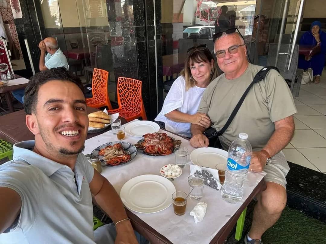 Driver-guide taking a selfie with a couple over a grilled lunch in a local restaurant