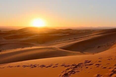 Golden sand dunes of the Sahara Desert in Morocco at sunset, where warm days give way to cold nights