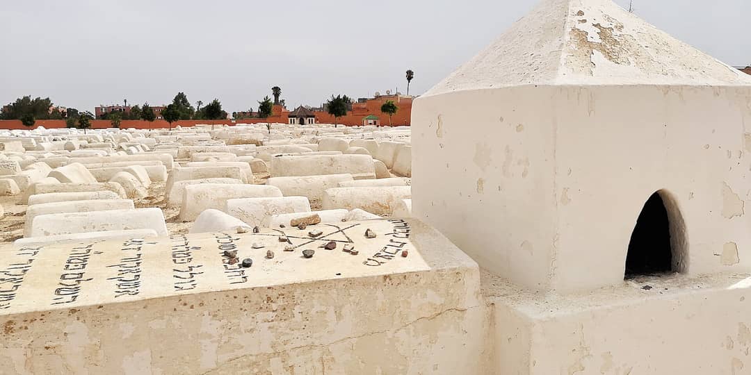 Rows of whitewashed graves in the Miâara Jewish Cemetery, Marrakech, with rabbis’ mausolea along the wall