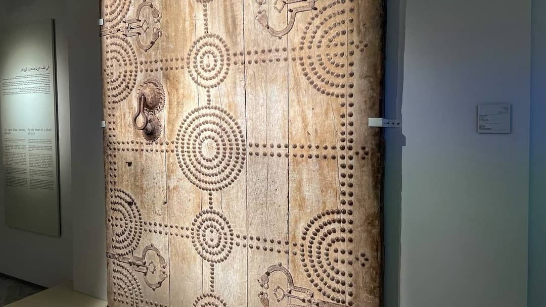 Large wooden door decorated with circles of iron studs, displayed in the Museum of Moroccan Jewish Culture in Fes