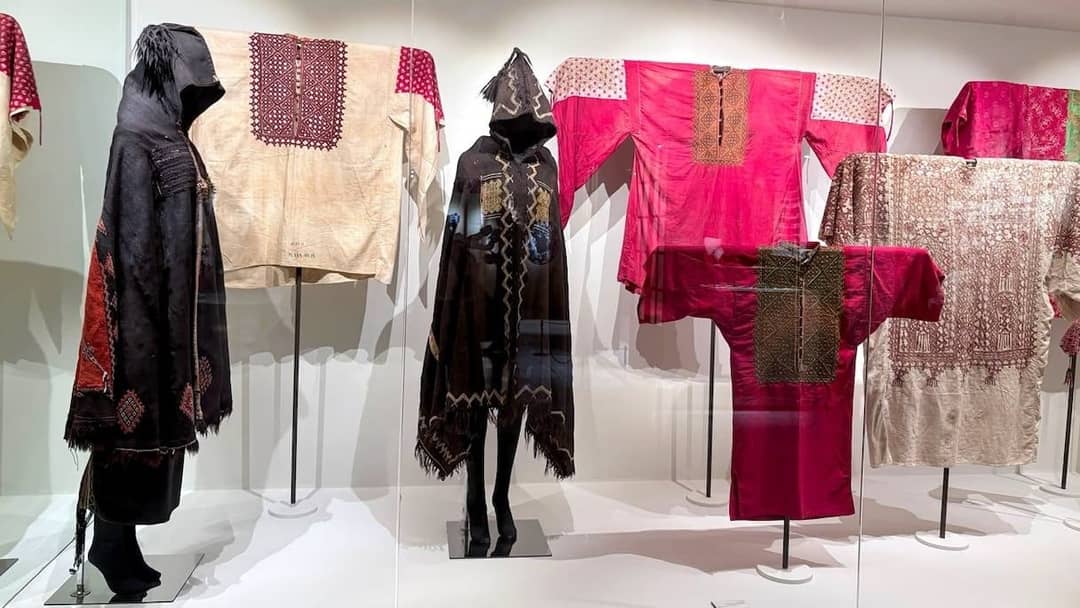Embroidered tunics and hooded black cloaks displayed in the costume gallery of the Fes Jewish museum