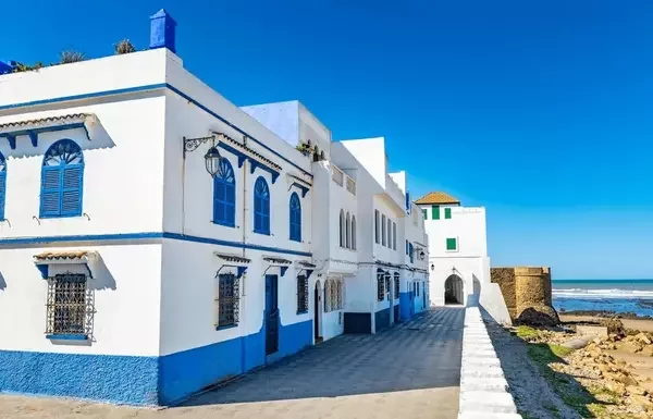Whitewashed medina walls with colorful murals in Asilah Morocco by the sea