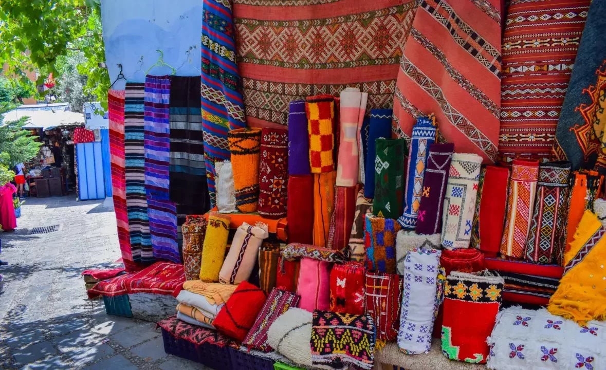 Colorful Moroccan rugs on display at a bustling local market – guided Morocco cultural and shopping tour
