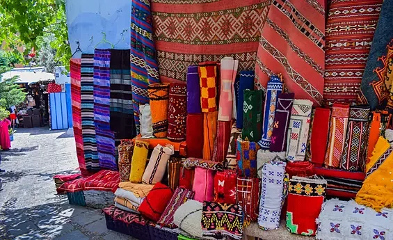 Colorful Moroccan rugs on display at a bustling local market – guided Morocco cultural and shopping tour