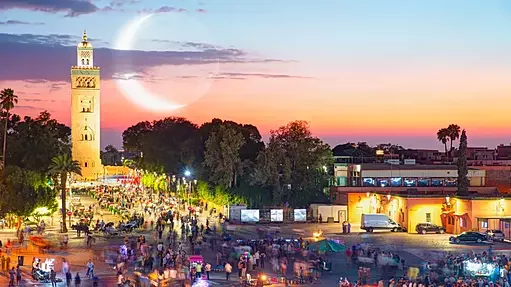 Aerial view of the vibrant Jemaa el-Fna square in Marrakech, featuring food stalls and storytellers at sunset.