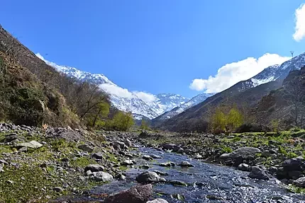 Stunning panoramic view of a winding road through the green peaks of the High Atlas Mountains, often for trekking tours.