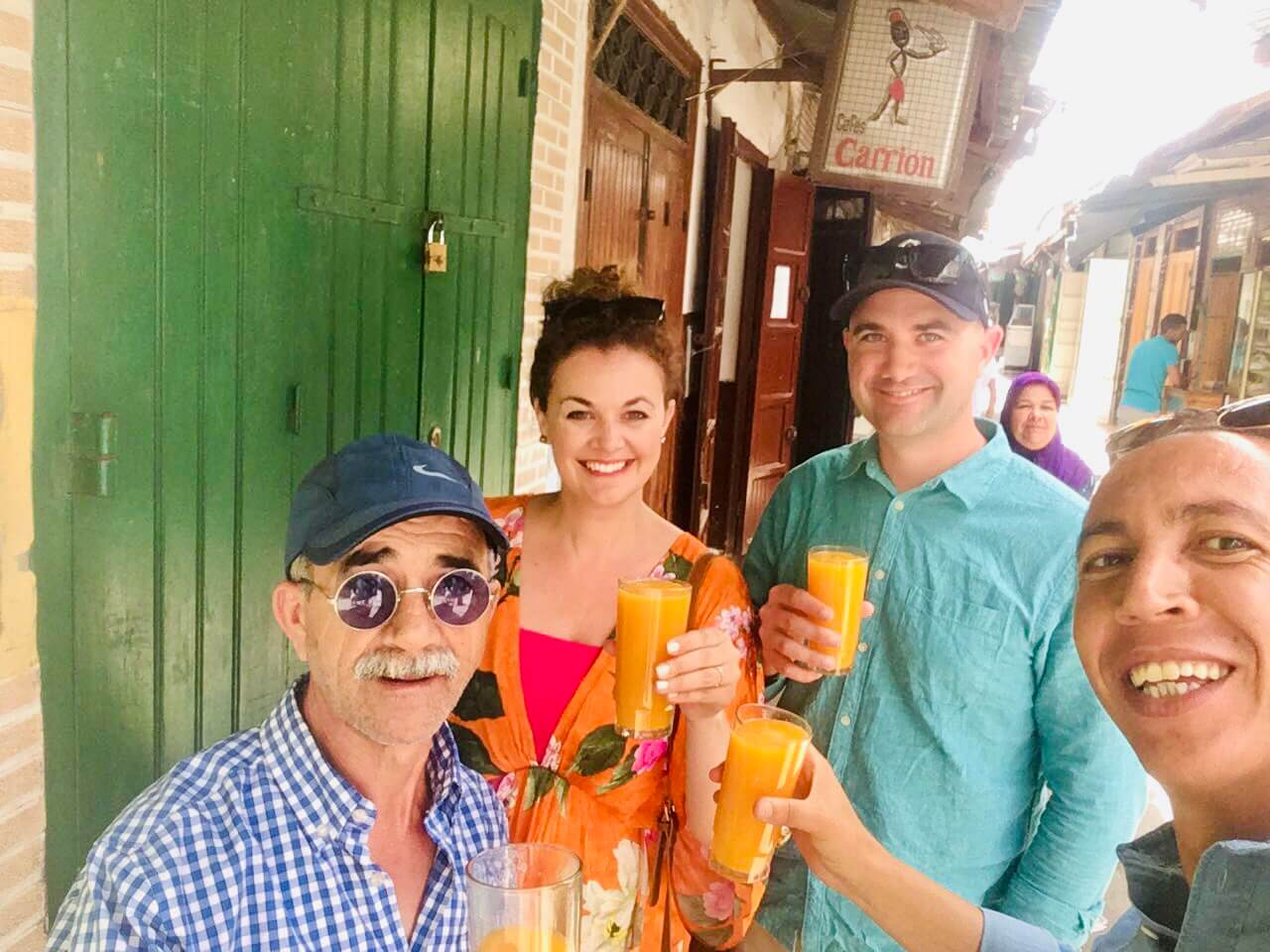 Happy travellers in Morocco with our private driver, relaxing and enjoying fresh squeezed orange juice during a customized Morocco tour.